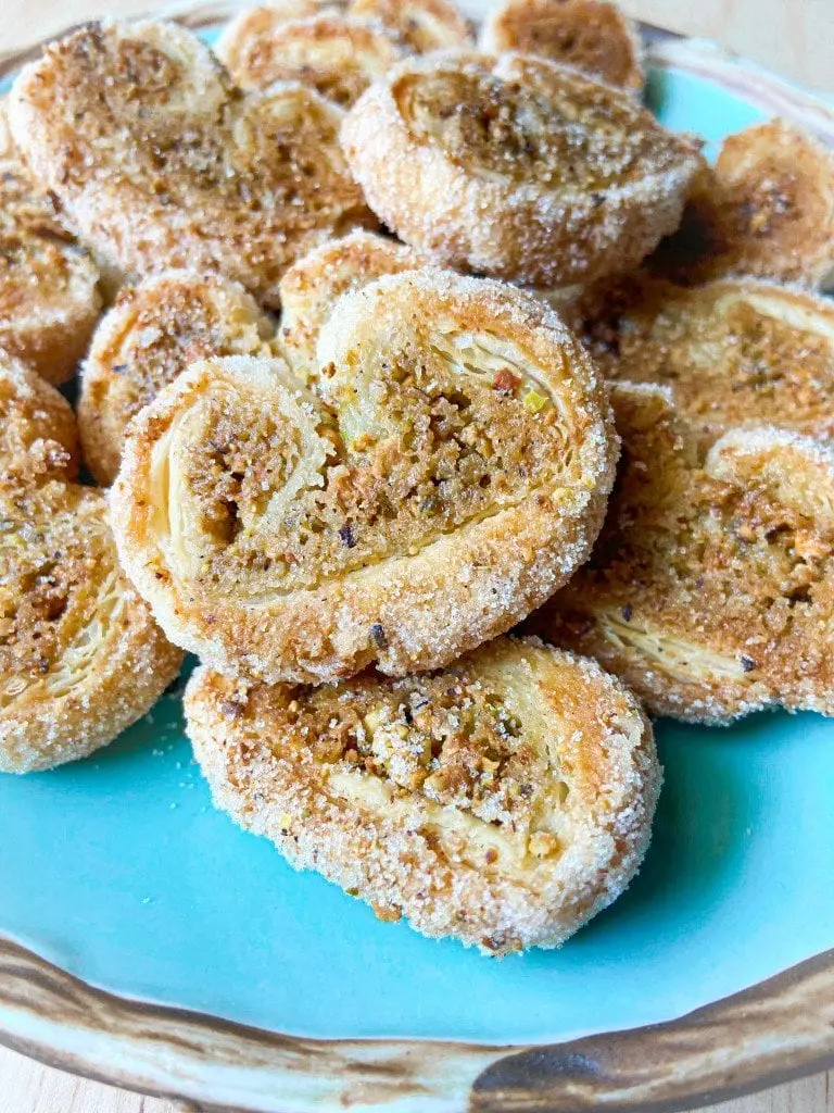 A close-up of pistachio palmiers on a plate.