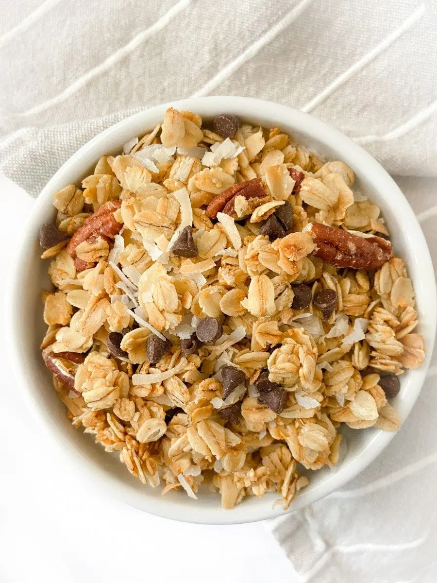 A white bowl of coconut chocolate chip granola. 