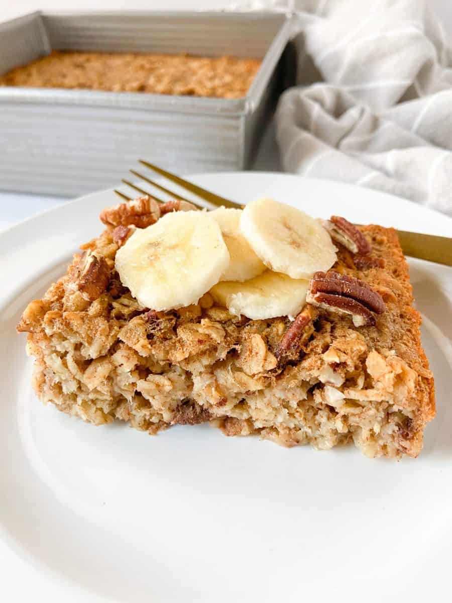 A single banana bread baked oatmeal slice on a white plate with a fork. 