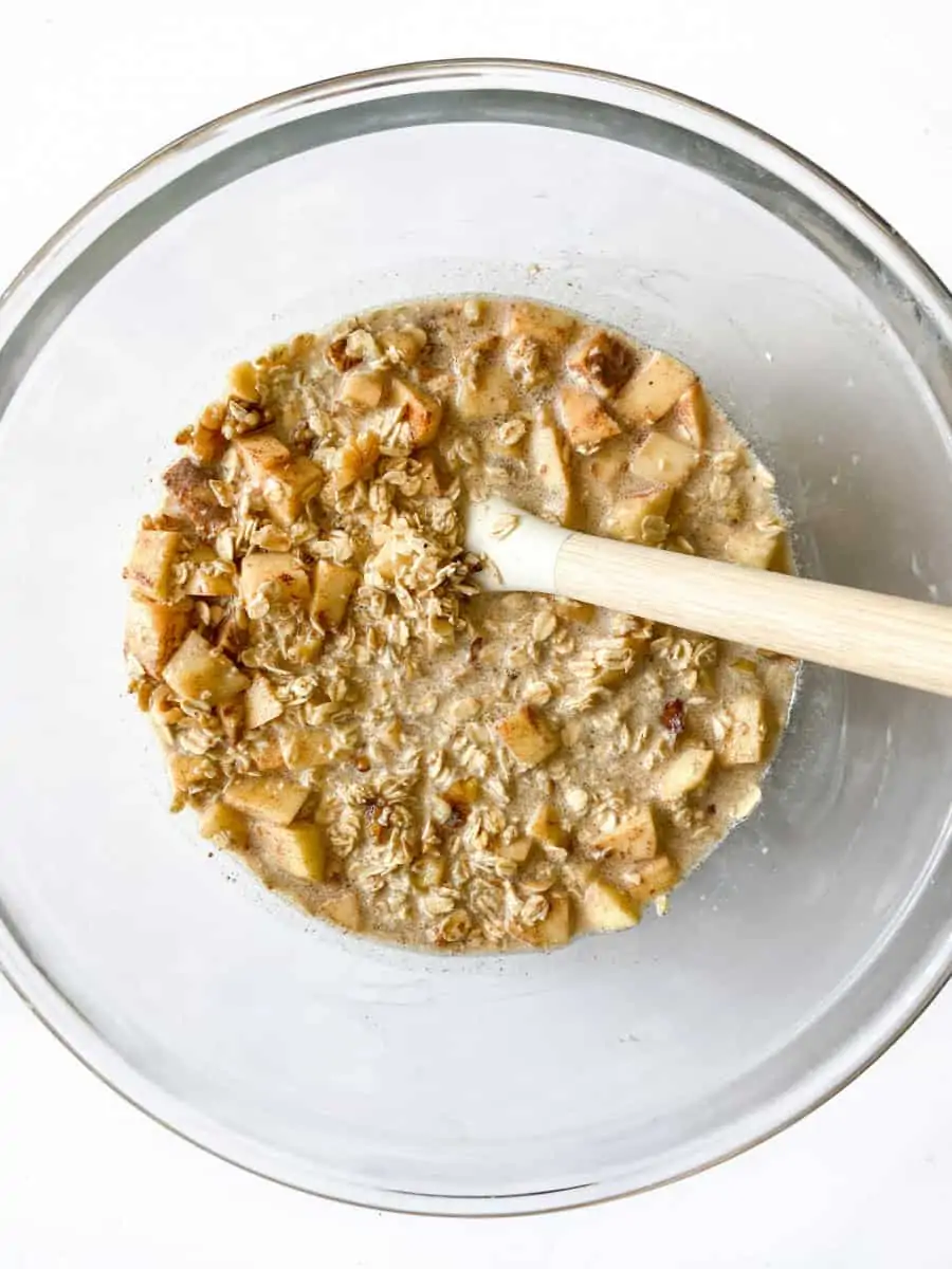 Baked oatmeal mixture in a bowl with a rubber spatula.