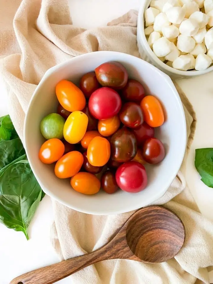 Ingredients in Caprese salad: heirloom cherry tomatoes, basil and mozzarella pearls