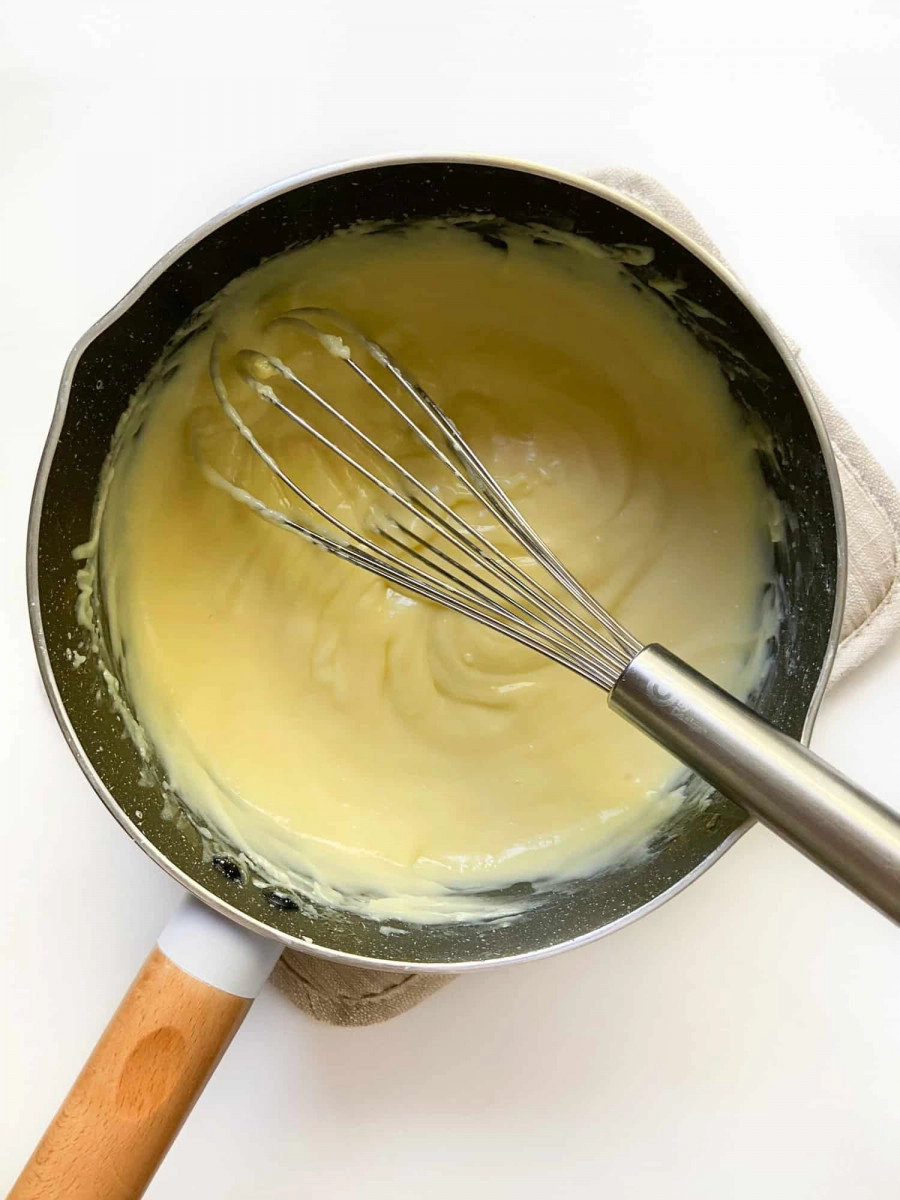 Thickened custard in a small saucepan with a whisk.