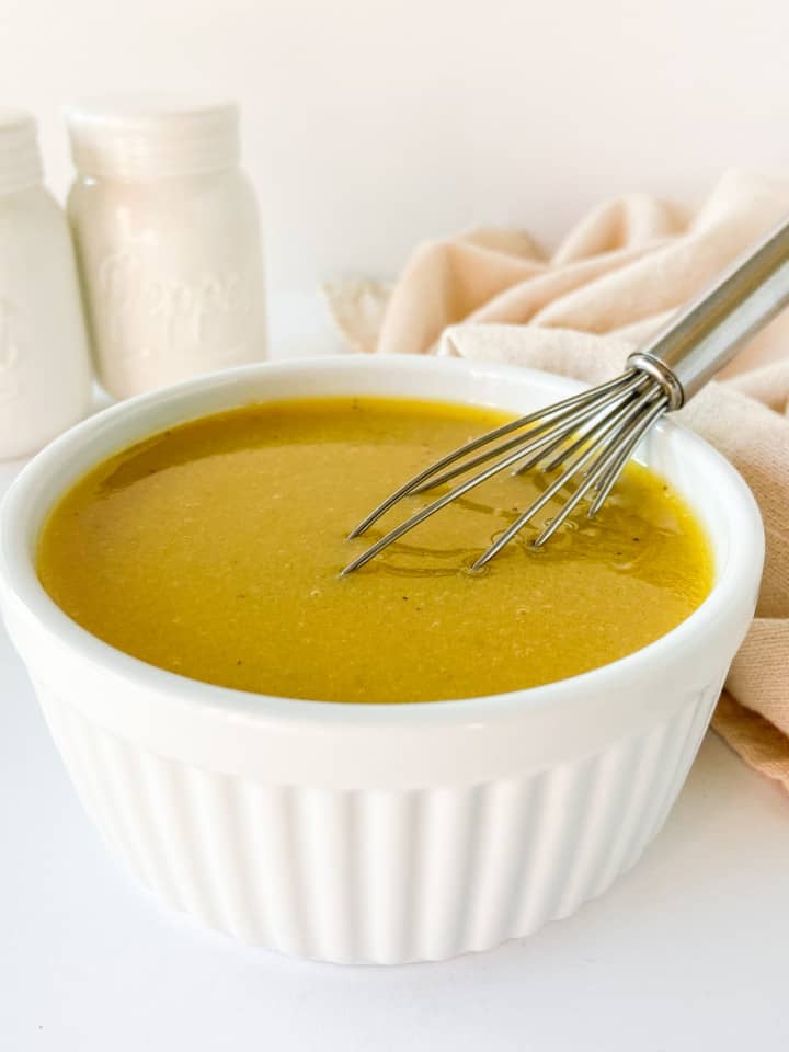 A close-up shot of salad dressing with a small whisk.