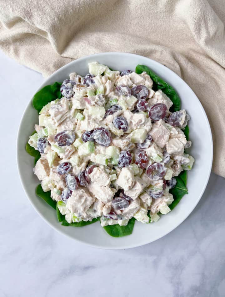 A white bowl with spinach and chicken salad.
