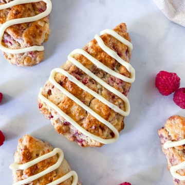Scones sporadically laid out with fresh raspberries.