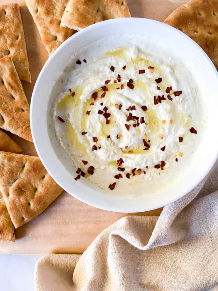 Roasted Garlic Whipped Feta Dip in a white bowl with toasted pita wedges.