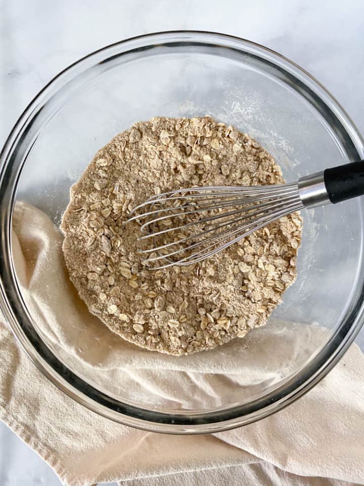A clear bowl filled with the mixed dry ingredients and a whisk.