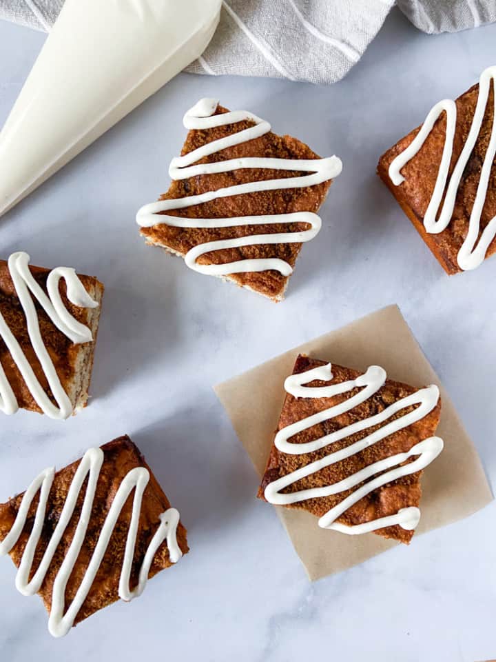Iced coffee cake slices spread out on marble with an icing filled pastry bag.