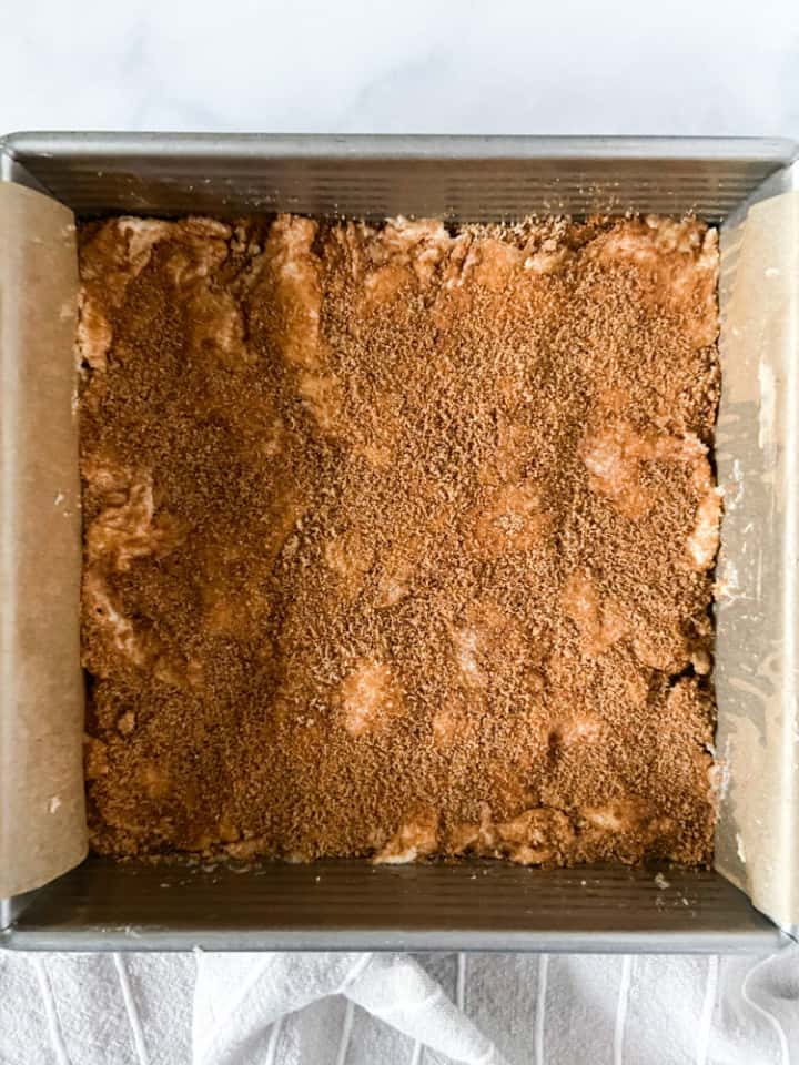 A cake pan filled with batter and sprinkled with cinnamon sugar.