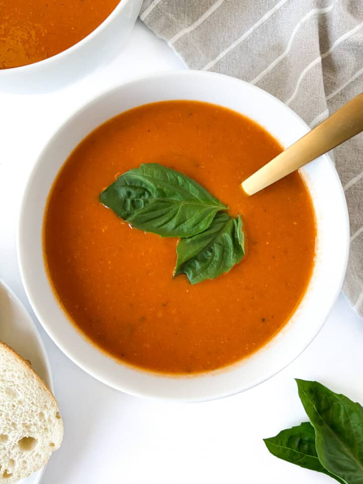 A bowl of tomato soup garnished with fresh basil.