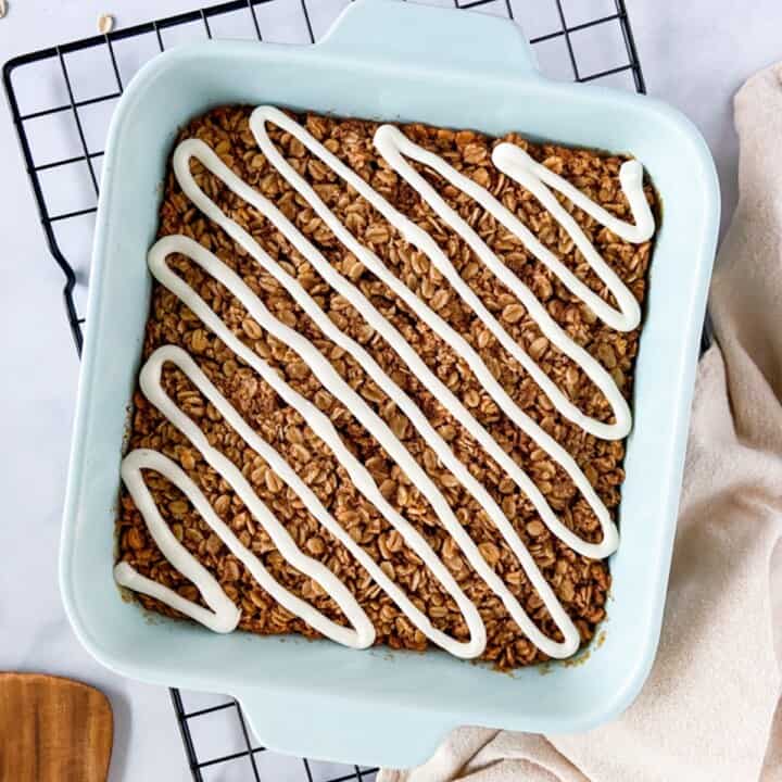 A pan of cinnamon baked oatmeal with cream cheese icing.