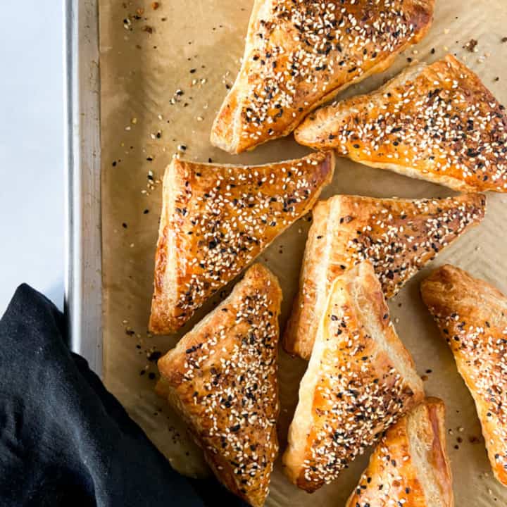 Everything bagel turnovers on a parchment lined baking sheet.