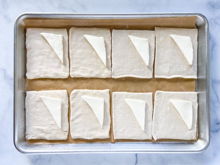 Puff pastry squares with a triangle of cream cheese on one half of each square.