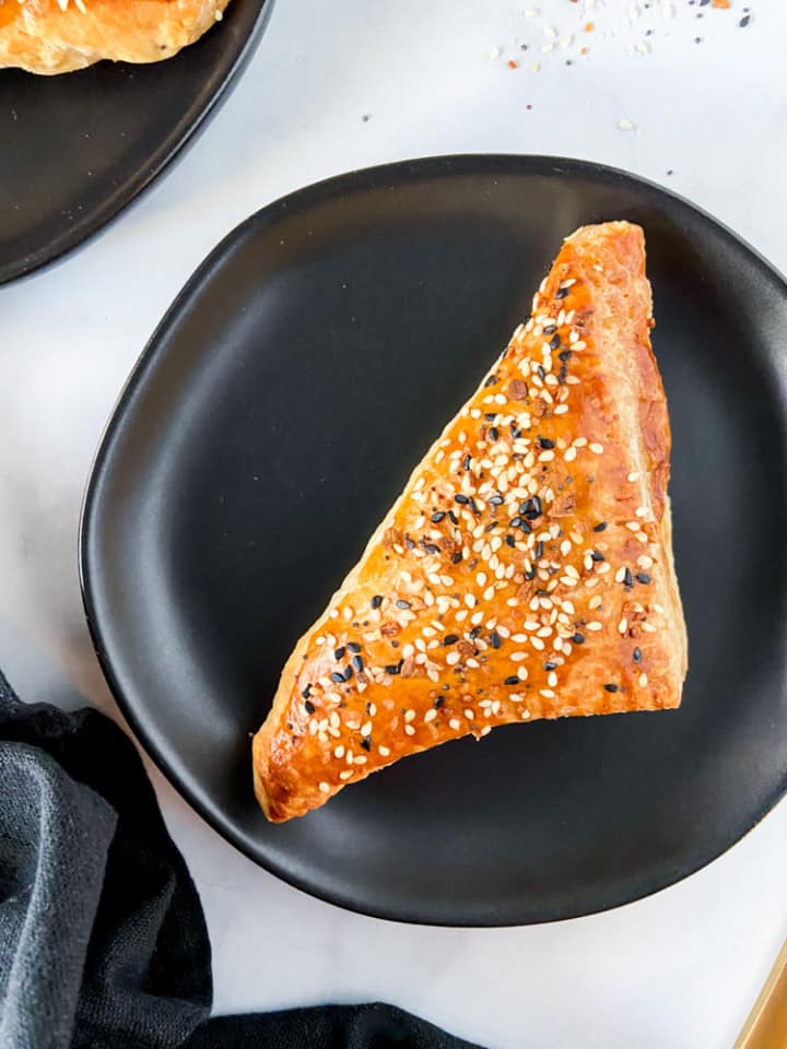 A cream cheese turnover on a small black plate.