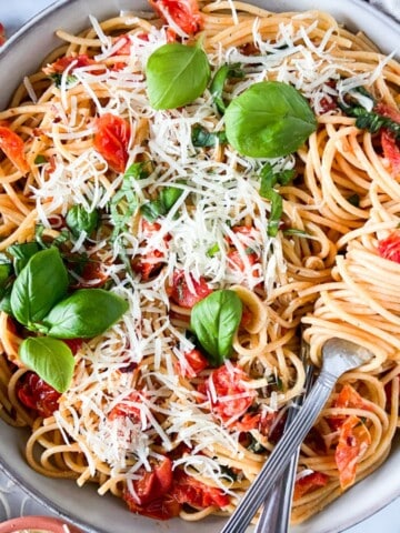 A large bowl of tomato basil pasta with two forks.