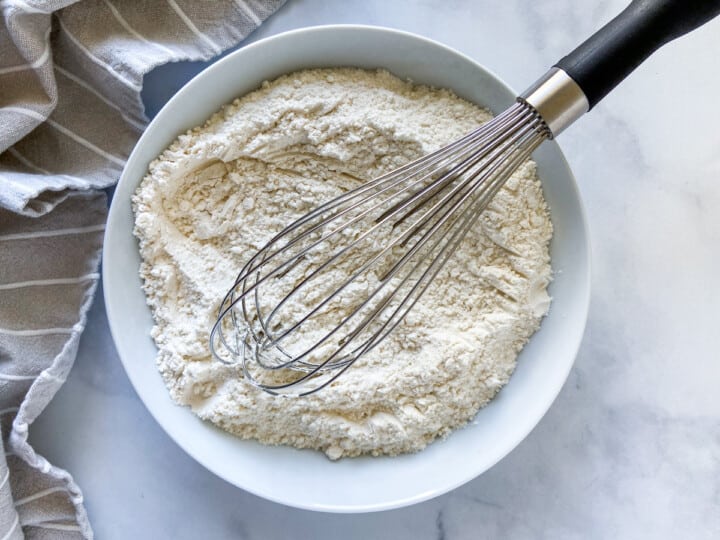 The dry ingredients in a white bowl with a whisk.