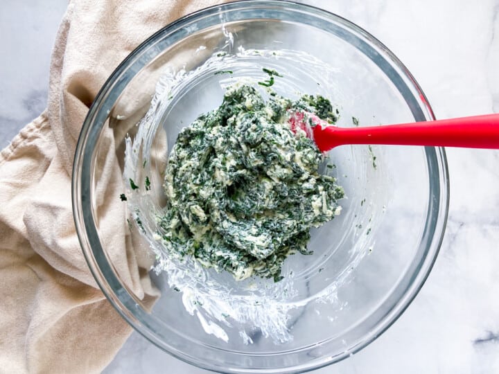The spinach-cheese mixture in a clear bowl with a spatula.