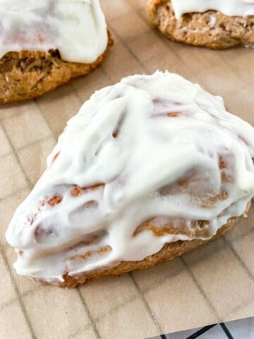 Cream cheese frosted cinnamon roll scones on a cooling rack.