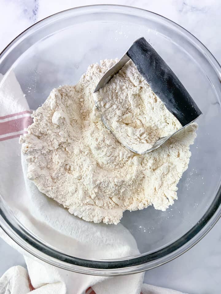 Dry ingredients in a bowl with butter and a pastry blender.