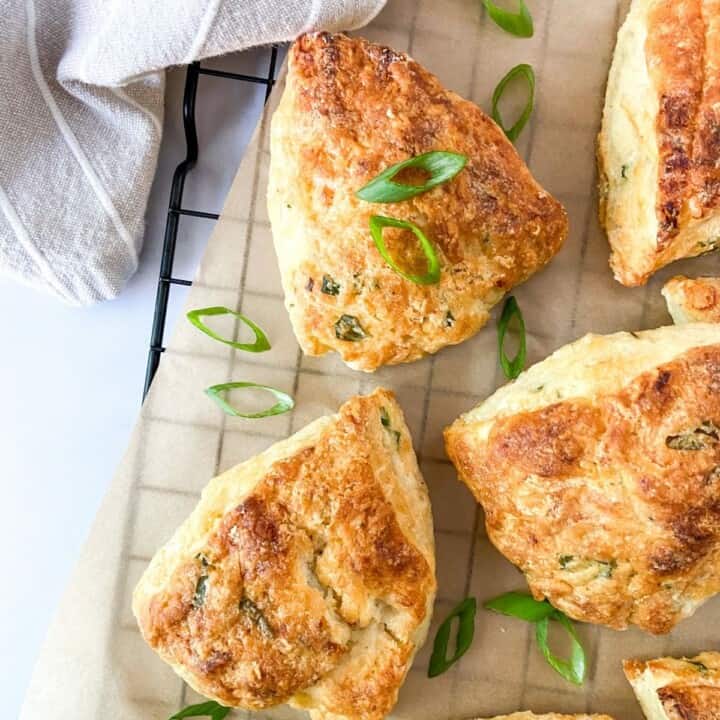 Goat cheese scones on a parchment-lined cooling rack with scallions.