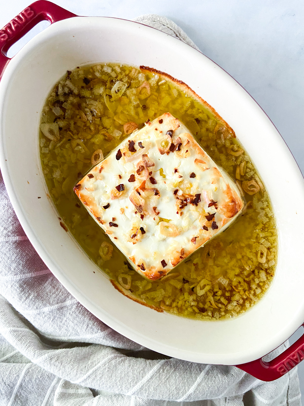 Baked feta with olive oil in a dish.
