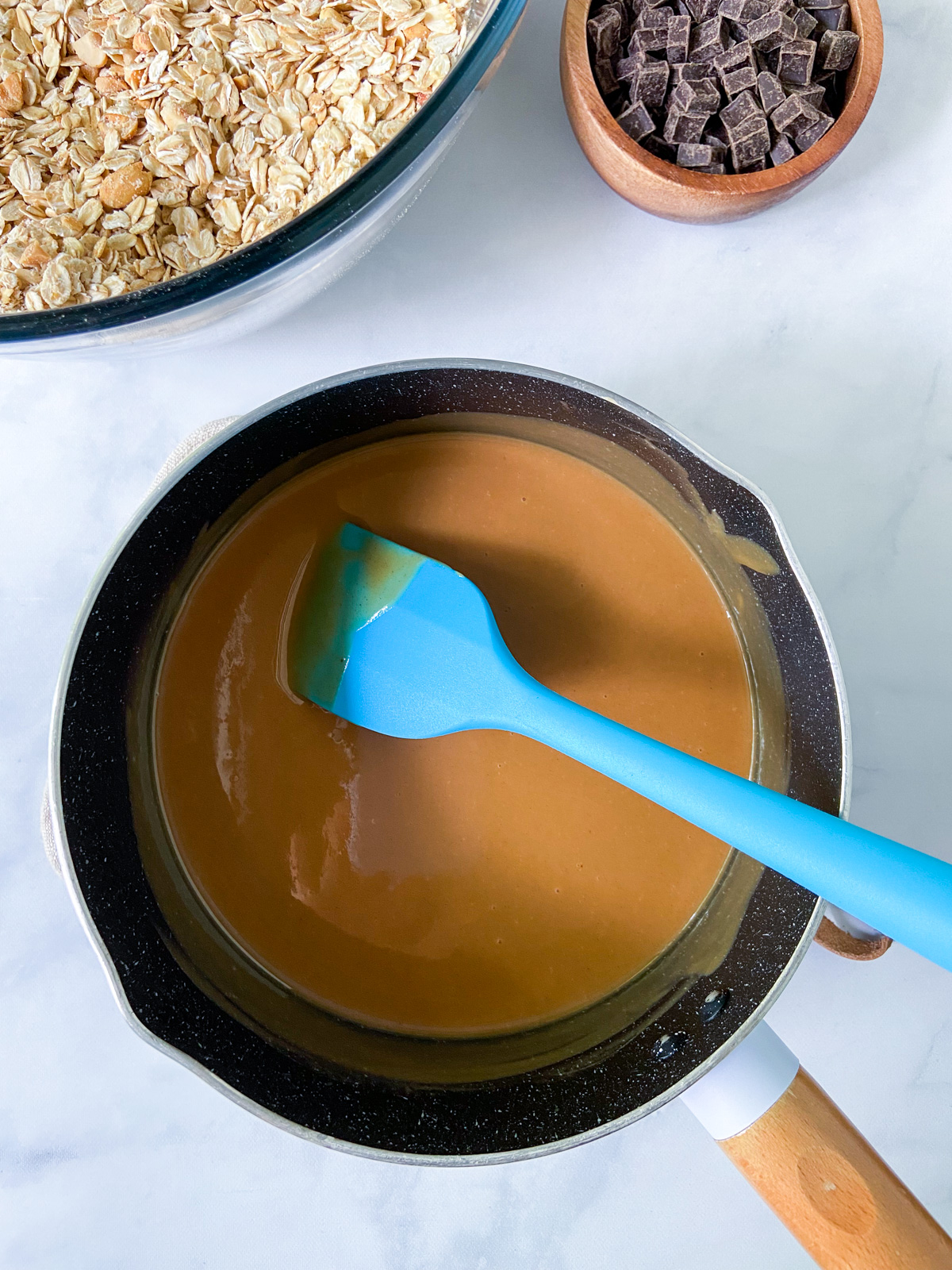 Melted peanut butter mixture in a small saucepan with a spatula.