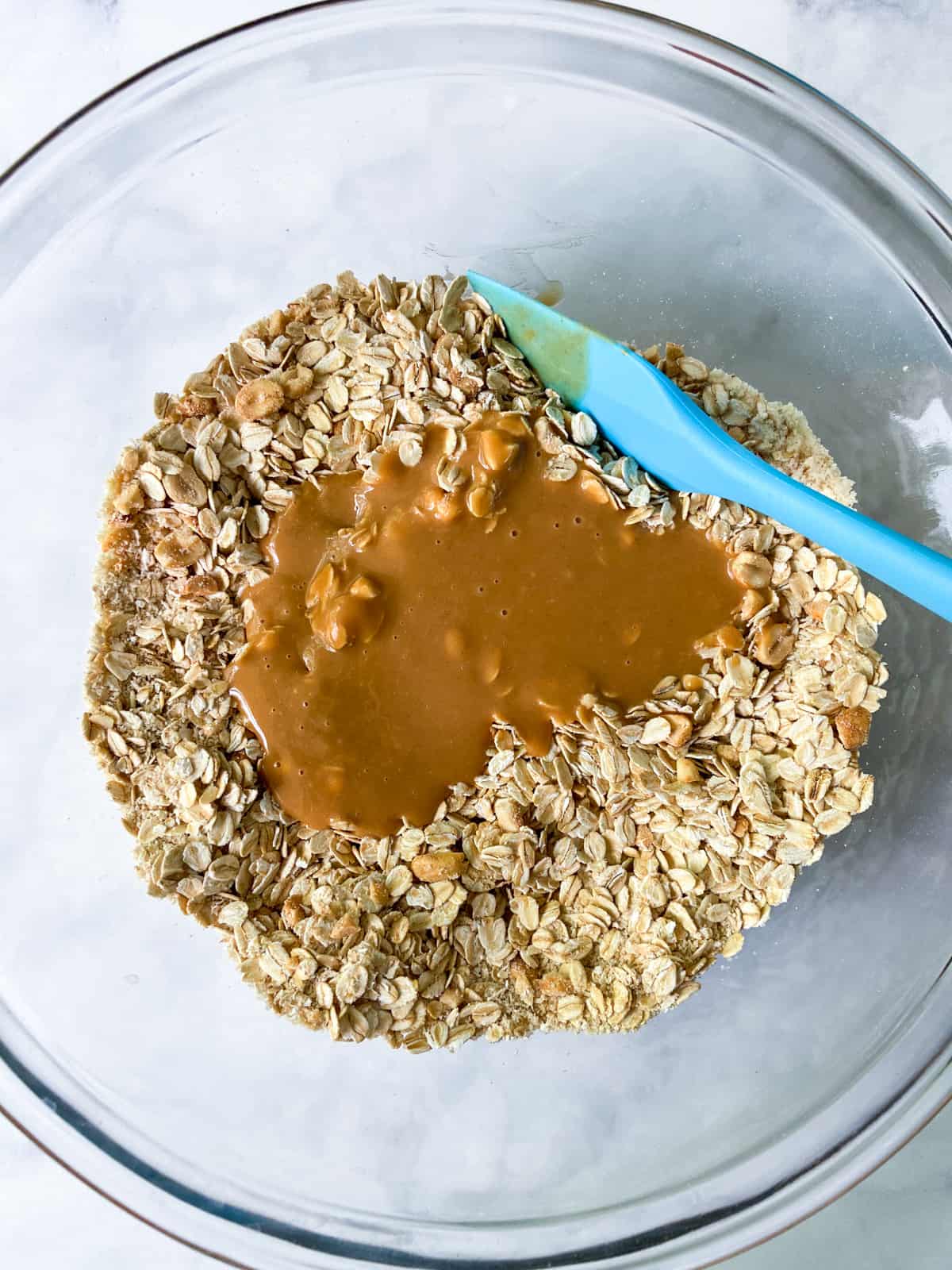 Melted peanut butter mixture poured over the dry ingredients in a bowl.