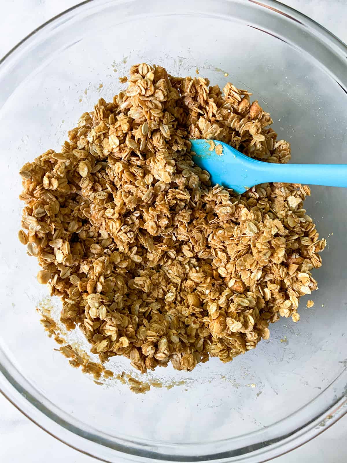 Unbaked granola in a bowl with a spatula.