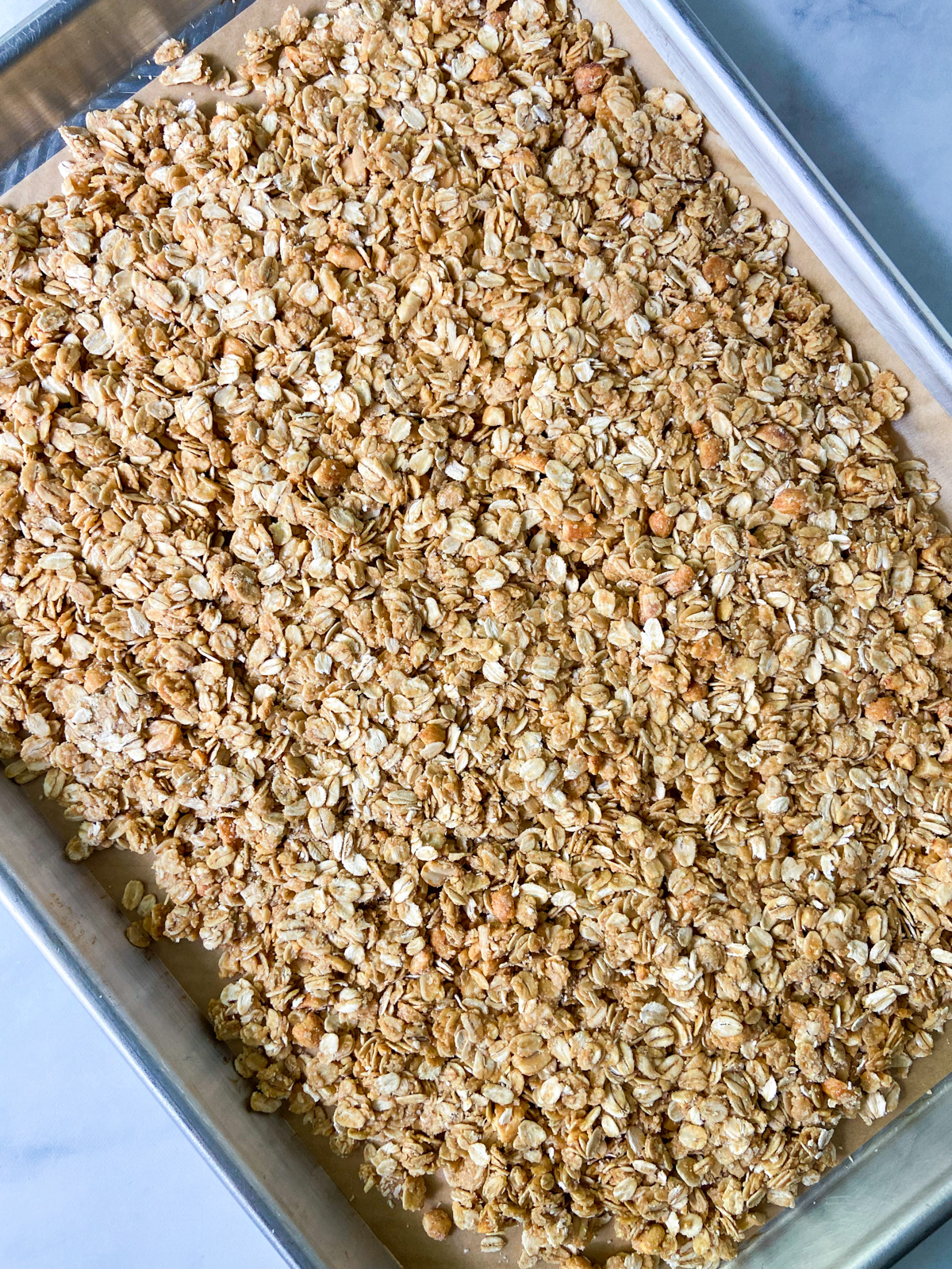 Baked granola on a parchment-lined tray.