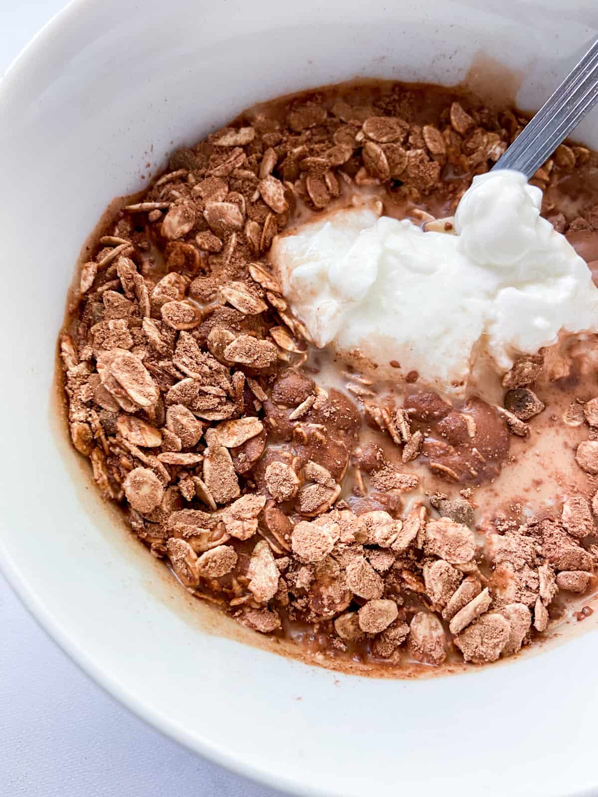Dry ingredients with yogurt and milk added in a bowl.