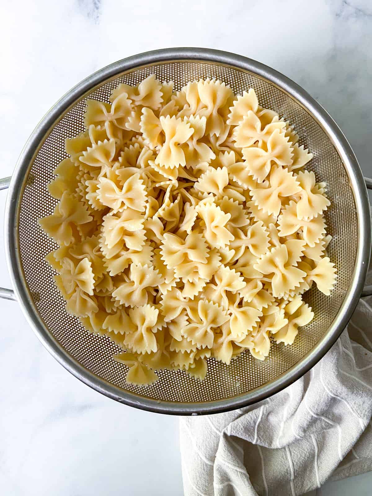 Cooked farfalle pasta in a strainer.