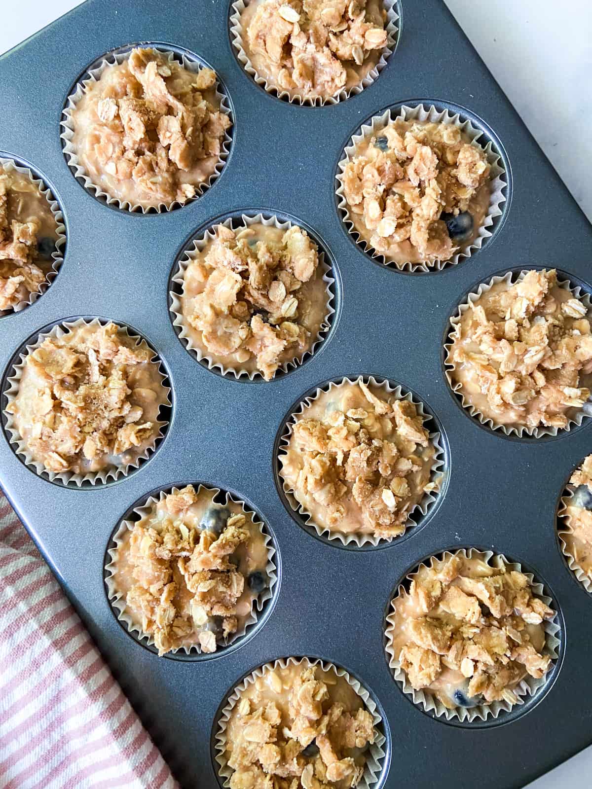 Unbaked muffins with streusel in a muffin tin.