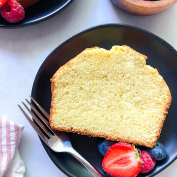 A slice of vanilla buttermilk pound cake on a plate with berries.