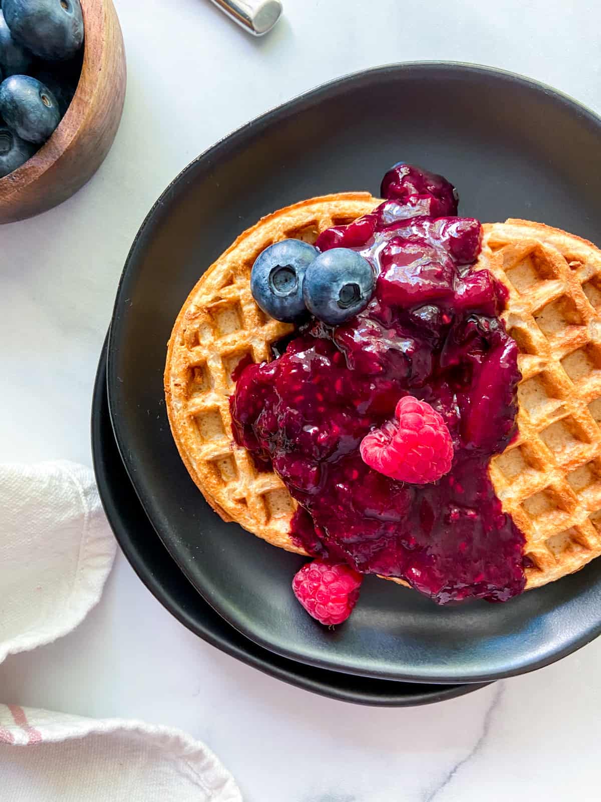 Waffles topped with mixed berry compote and fresh berries.