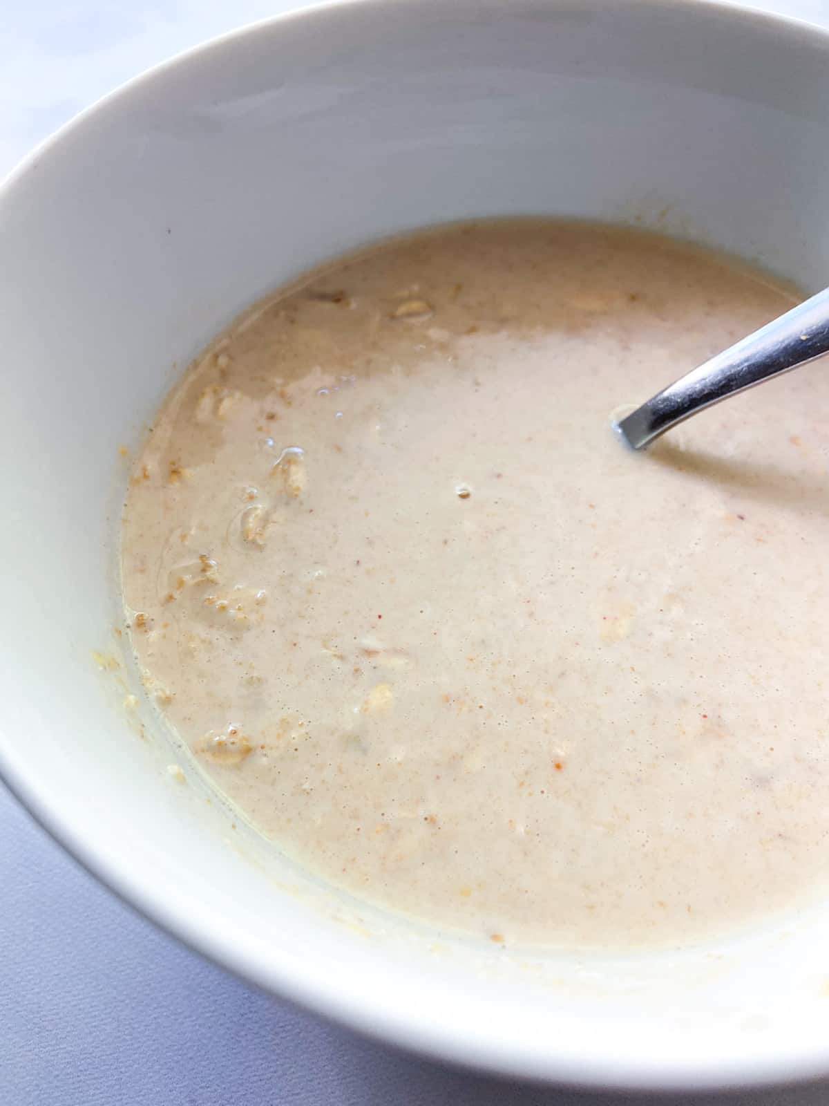 The overnight oats mixture in a bowl with a spoon.