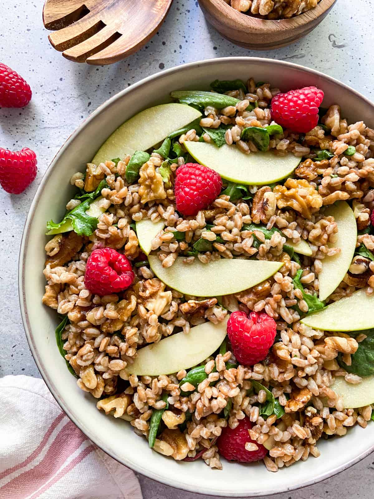 Healthy farro salad topped with fresh fruit in a large bowl.