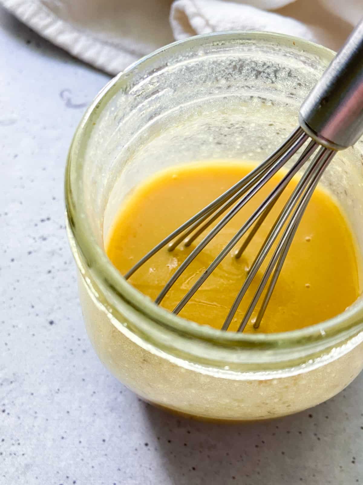 Honey mustard vinaigrette in a jar with a whisk.