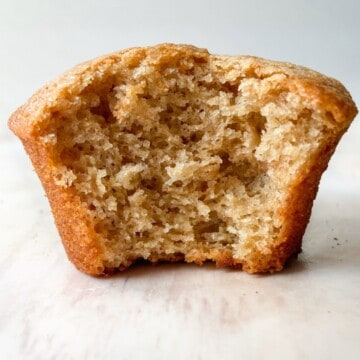 A banana protein muffin with a bite taken out of it.
