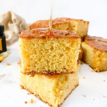 A stack of cornbread slices drizzled with honey.