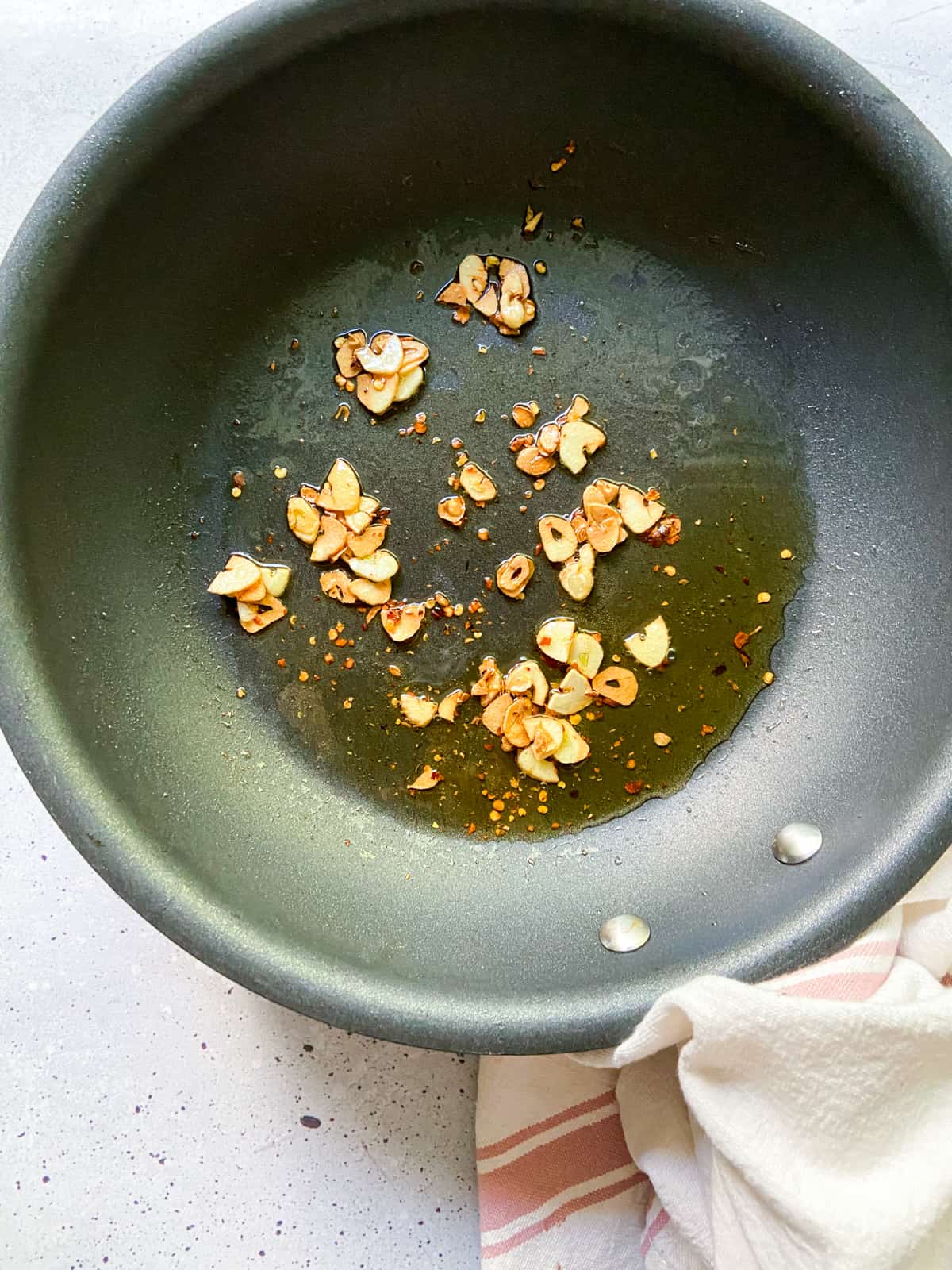 A skillet with fried garlic, crushed red pepper flakes, and olive oil.