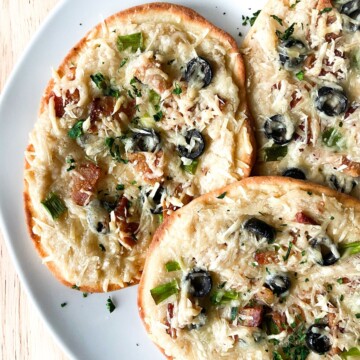 Three mini naan pizzas on a plate.