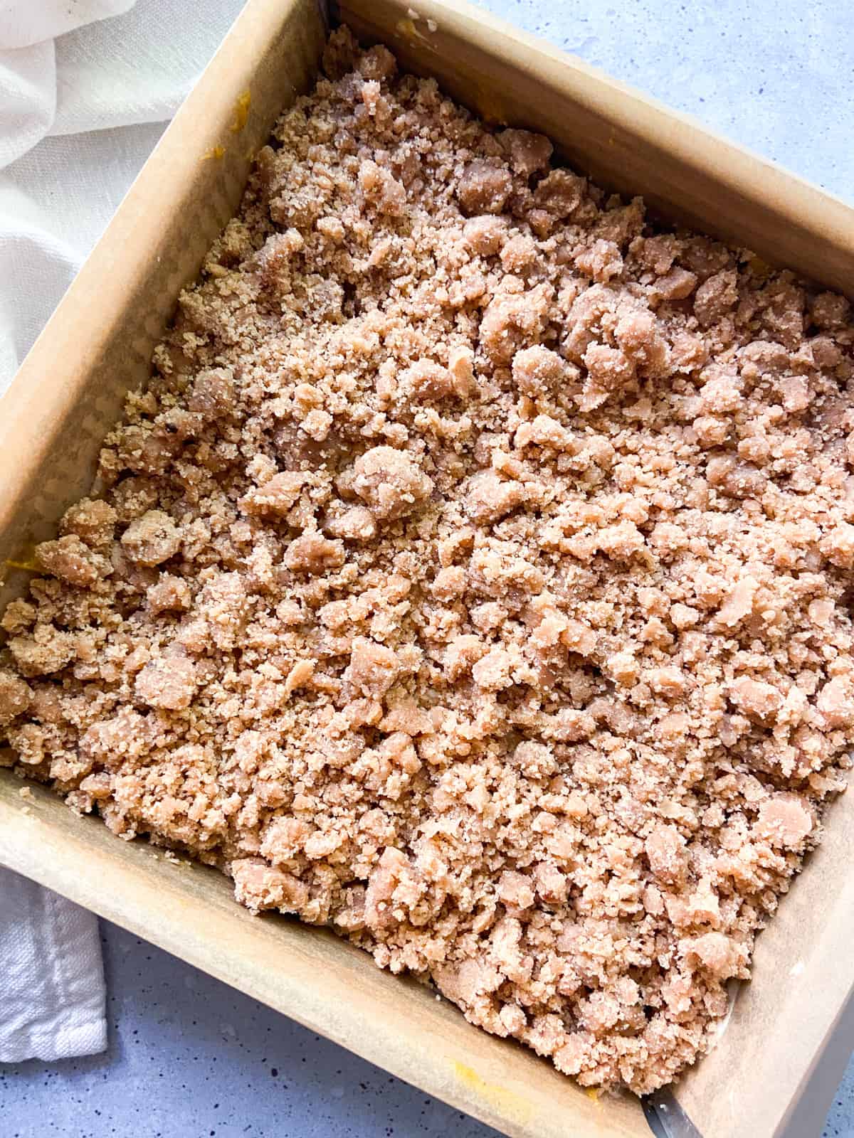Unbaked crumb cake in a parchment-lined cake pan.