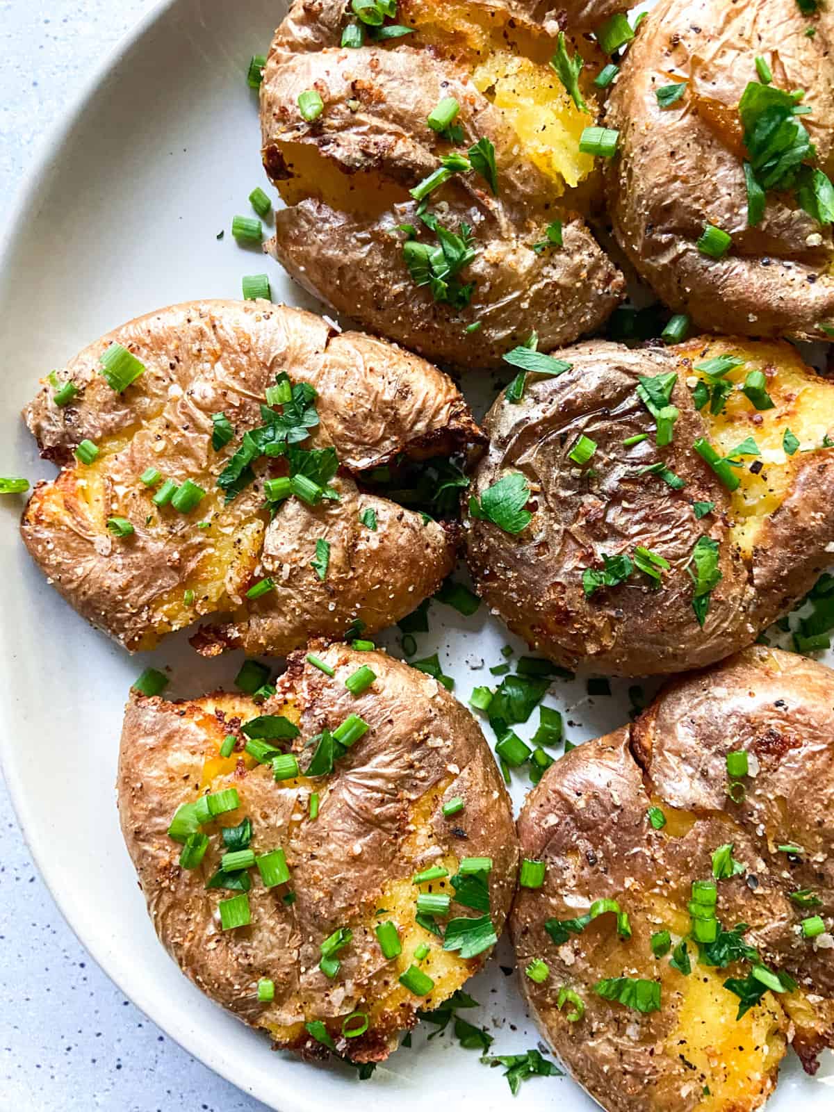 Smashed potatoes garnished with chives.