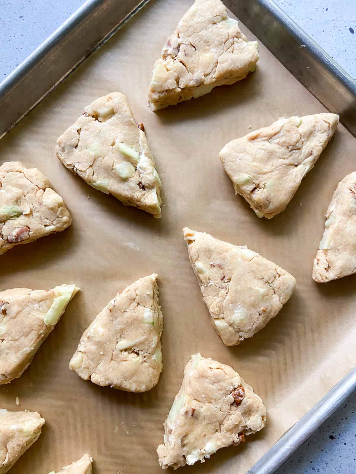 Unbaked triangle cut scones on a parchment-lined tray.