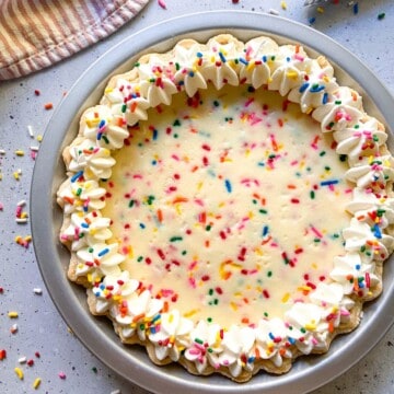 A funfetti cream cheese pie garnished with whipped cream and sprinkles.