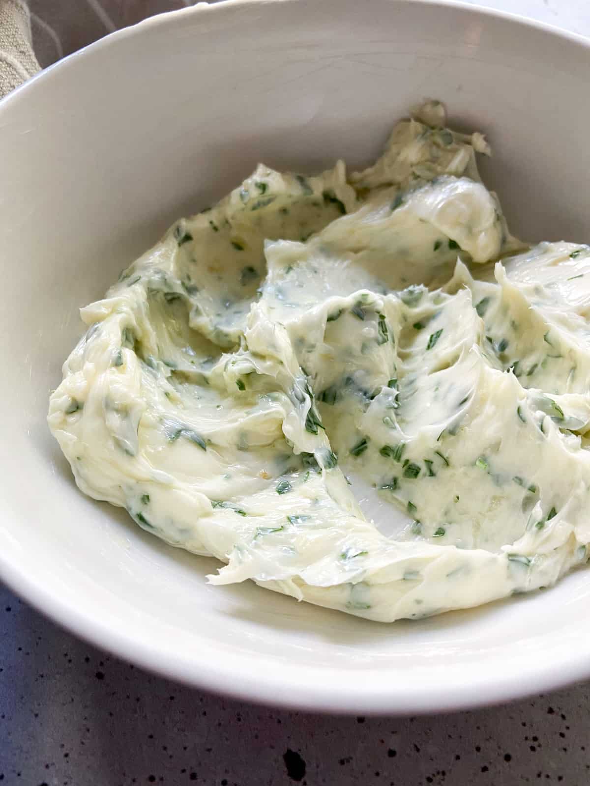Softened butter in a bowl with garlic and parsley mixed in.