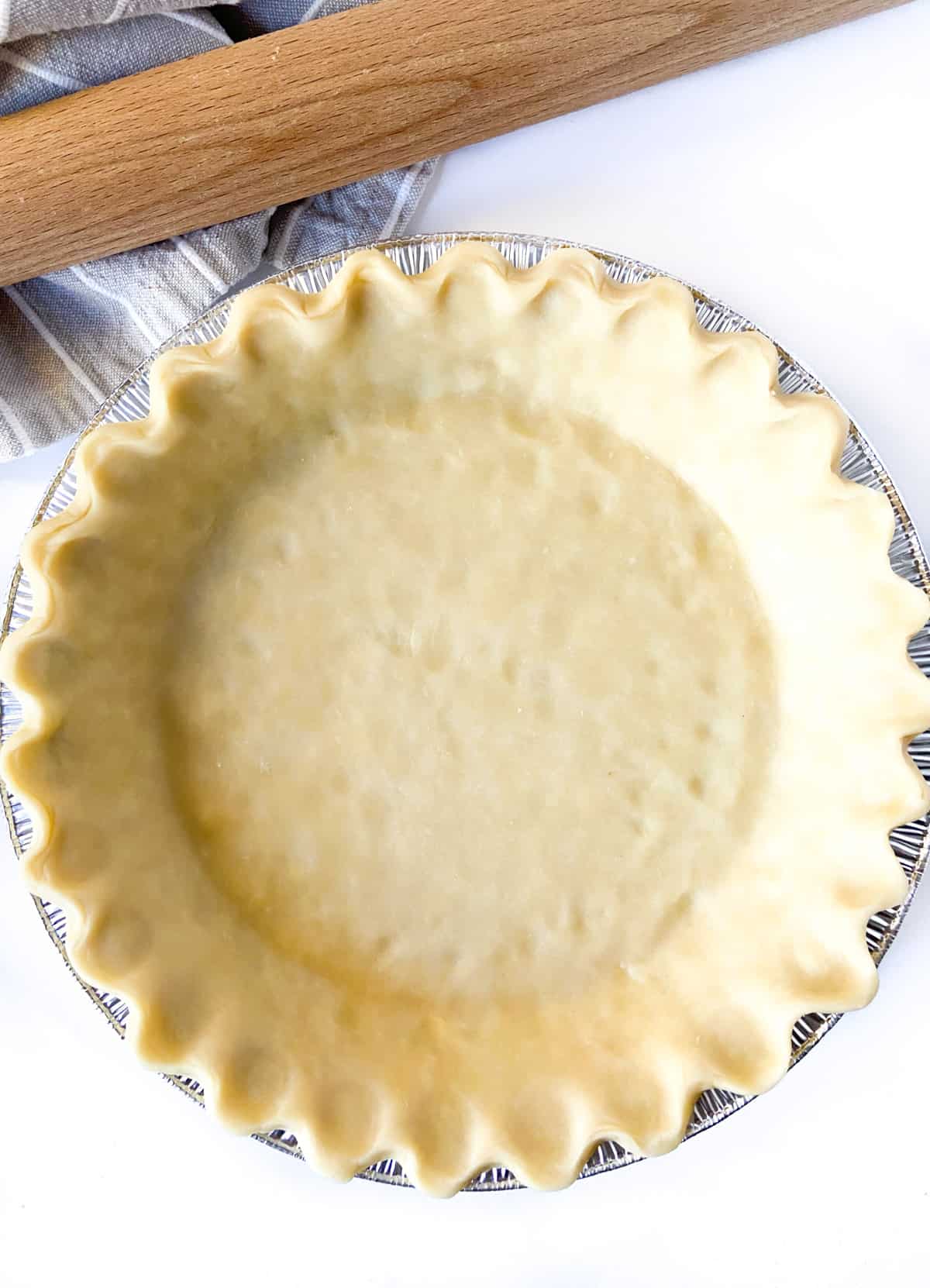 An unbaked pie crust in a foil pie tin.