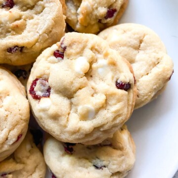 A pile of white chocolate cranberry cookies on a plate.