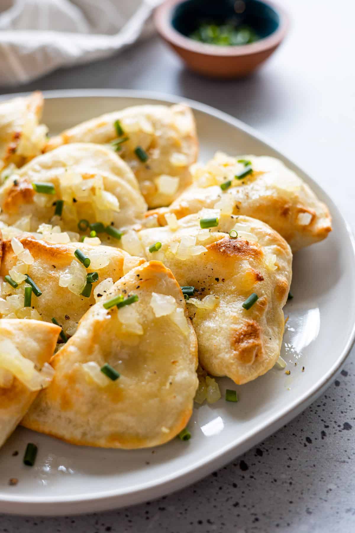 A plate of pierogies garnished with onions.