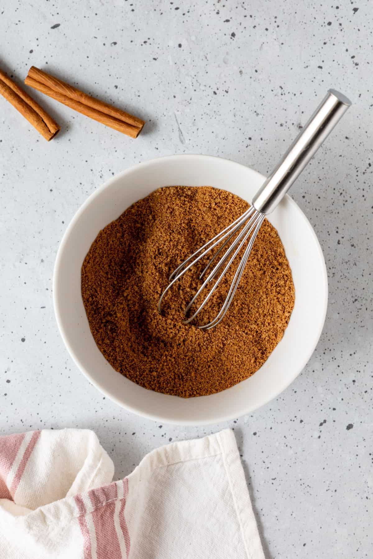 A bowl of cinnamon sugar with a small whisk.